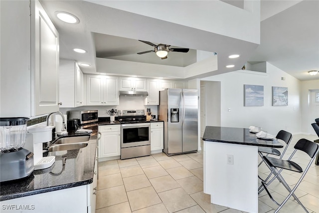 kitchen featuring white cabinets, a kitchen breakfast bar, sink, ceiling fan, and appliances with stainless steel finishes