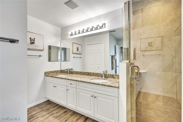 bathroom featuring hardwood / wood-style flooring, vanity, and a shower with door