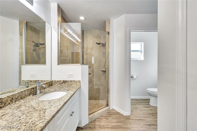 bathroom with vanity, hardwood / wood-style flooring, toilet, a textured ceiling, and a shower with shower door