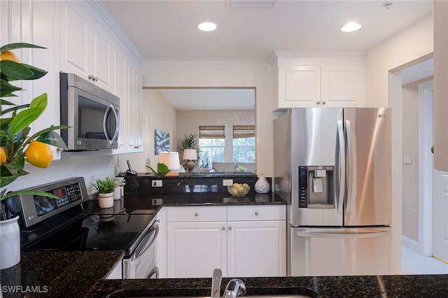 kitchen featuring white cabinets, stainless steel appliances, and dark stone counters