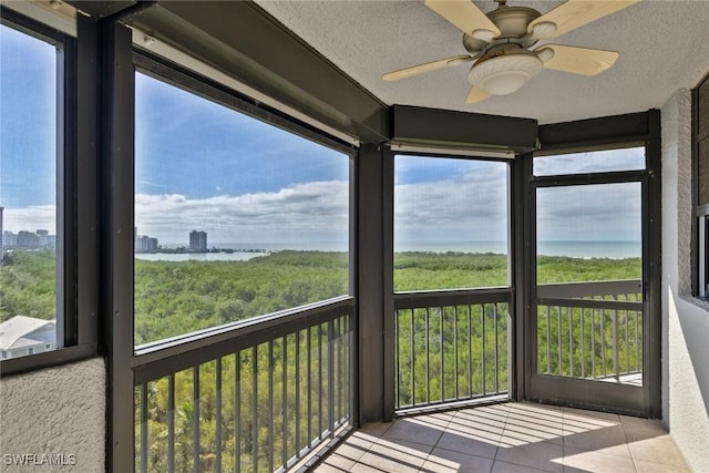 unfurnished sunroom featuring ceiling fan and a water view