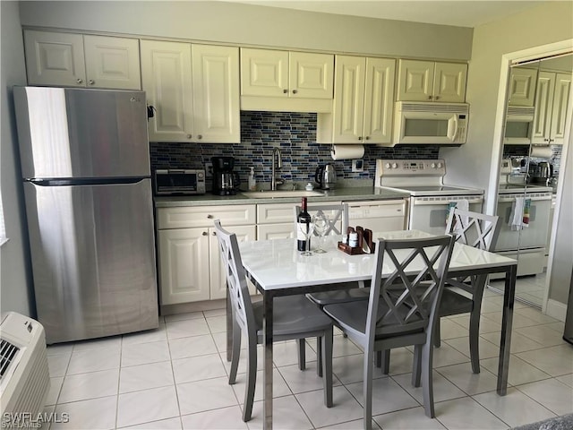 kitchen with light tile patterned floors, backsplash, sink, and white appliances