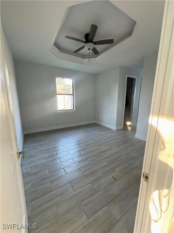 empty room featuring a raised ceiling and ceiling fan