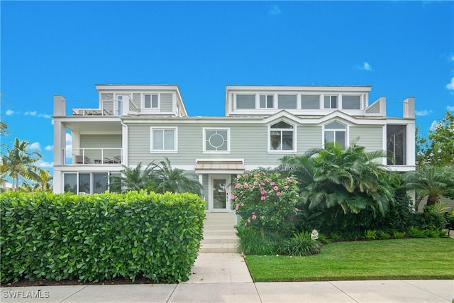 view of front of property featuring a front lawn and a balcony