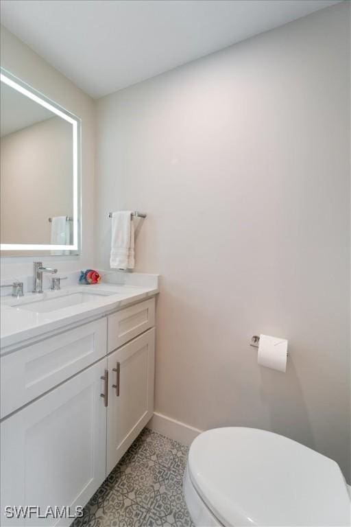 bathroom with toilet, vanity, and tile patterned flooring