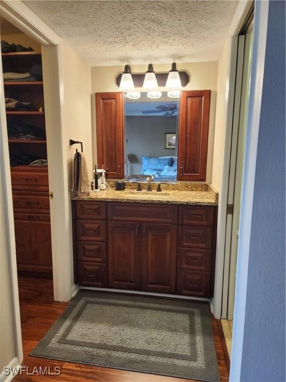 bar featuring a textured ceiling, dark hardwood / wood-style floors, and sink