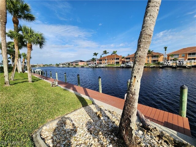 view of dock with a yard and a water view