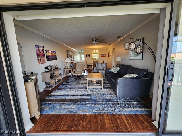 living room featuring a textured ceiling, dark hardwood / wood-style flooring, ceiling fan, and crown molding