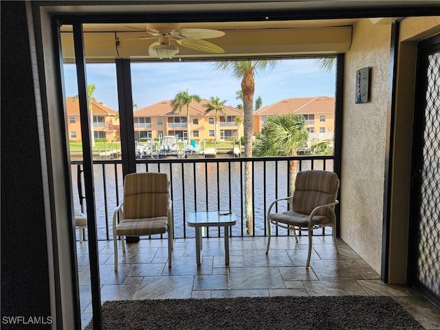 sunroom featuring ceiling fan and a water view