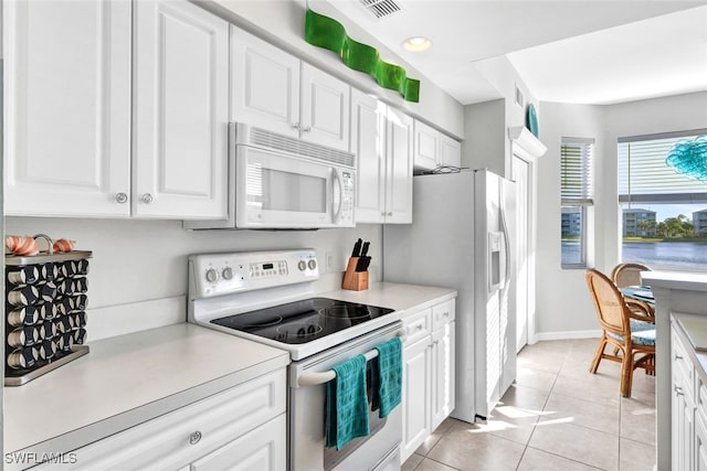 kitchen with white cabinets, light tile patterned flooring, and white appliances