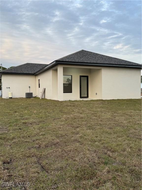 back of property featuring central air condition unit and a yard