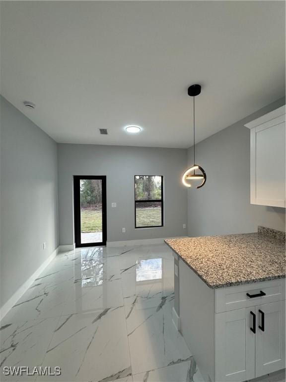 kitchen featuring white cabinets, pendant lighting, and light stone counters