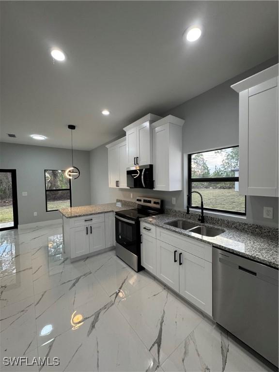 kitchen with appliances with stainless steel finishes, hanging light fixtures, kitchen peninsula, white cabinets, and sink