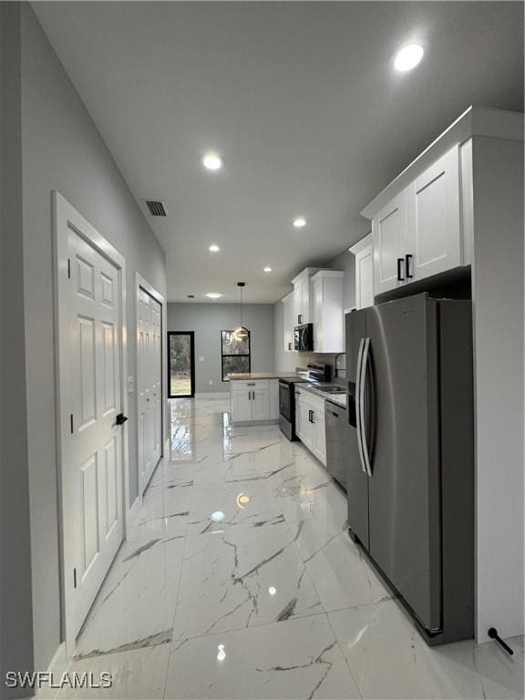 kitchen with decorative light fixtures, stainless steel appliances, and white cabinetry