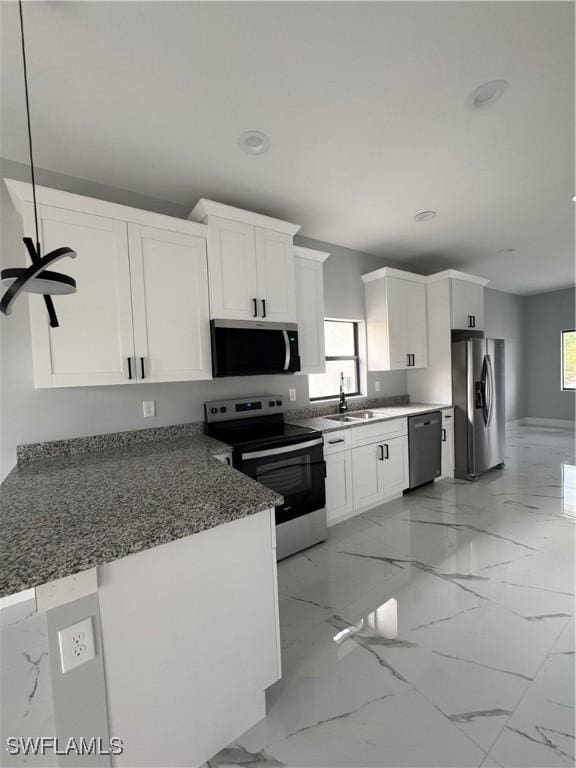 kitchen with stainless steel appliances, kitchen peninsula, sink, white cabinetry, and decorative light fixtures