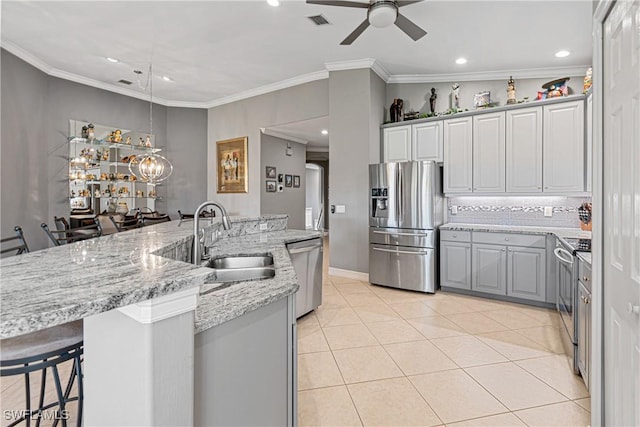 kitchen featuring a kitchen bar, appliances with stainless steel finishes, ceiling fan, sink, and gray cabinets