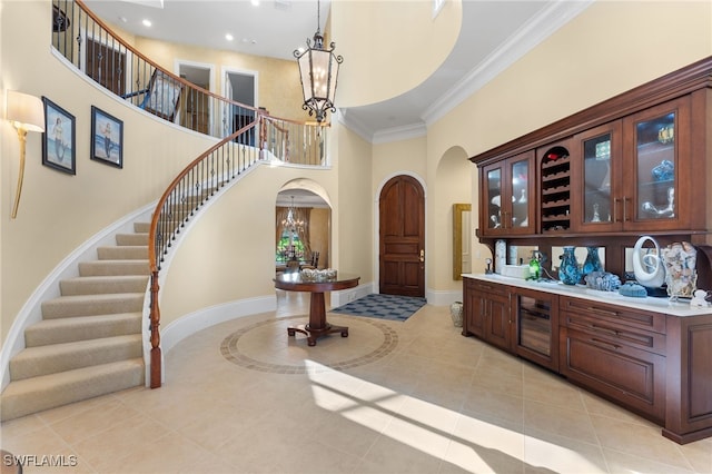 entrance foyer featuring ornamental molding, light tile patterned floors, a notable chandelier, and a high ceiling