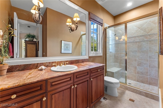 bathroom with tile patterned floors, vanity, a shower with shower door, and toilet