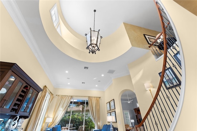 interior space with ceiling fan with notable chandelier and ornamental molding