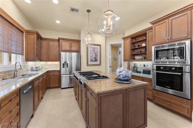 kitchen with decorative backsplash, stainless steel appliances, sink, decorative light fixtures, and a center island