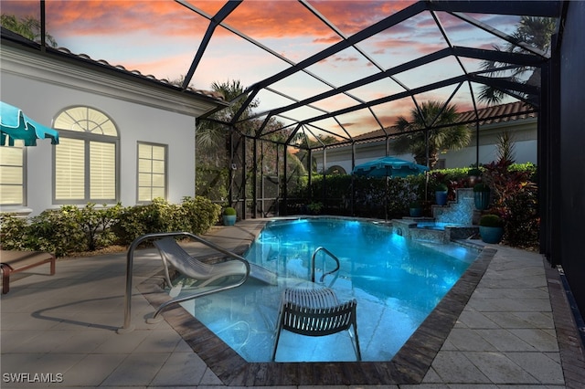 pool at dusk with pool water feature, glass enclosure, and a patio