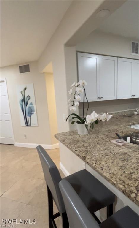 kitchen with light stone counters, light tile patterned floors, and white cabinets