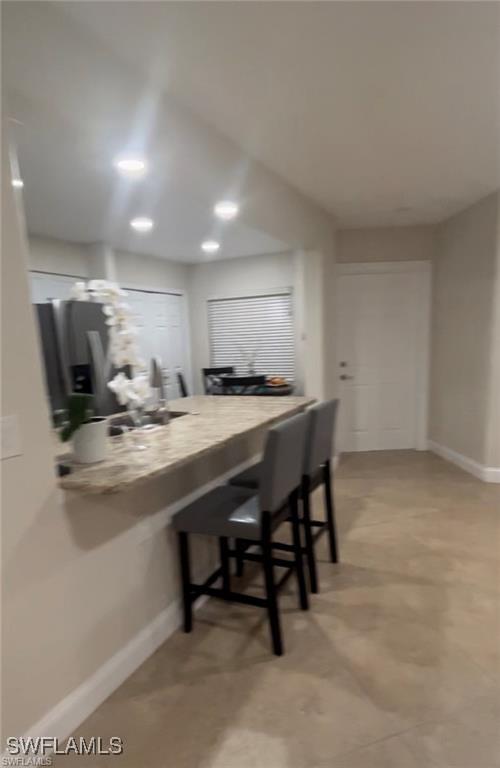 kitchen featuring stainless steel fridge with ice dispenser, kitchen peninsula, and a kitchen bar