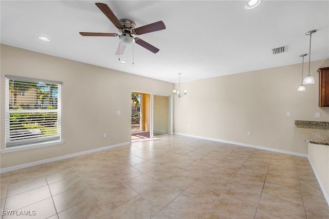 tiled empty room with ceiling fan with notable chandelier