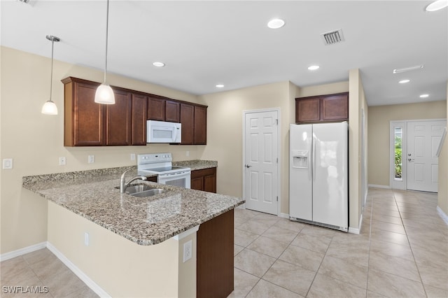 kitchen featuring sink, light stone counters, kitchen peninsula, decorative light fixtures, and white appliances