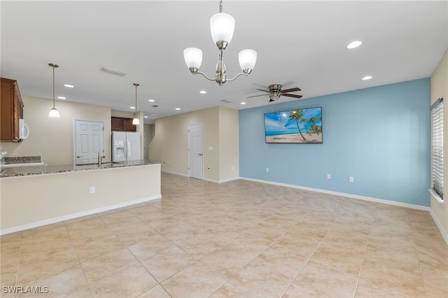 unfurnished living room featuring ceiling fan with notable chandelier, light tile patterned floors, and sink