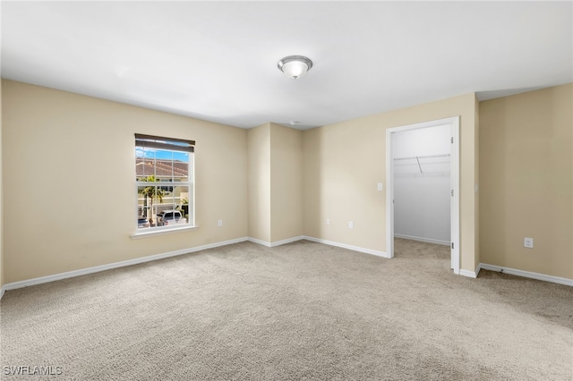 unfurnished bedroom with a spacious closet, a closet, and light colored carpet