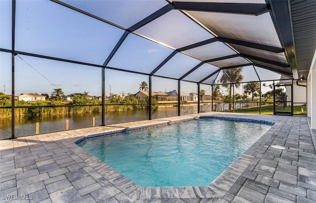 view of swimming pool with glass enclosure, a water view, and a patio