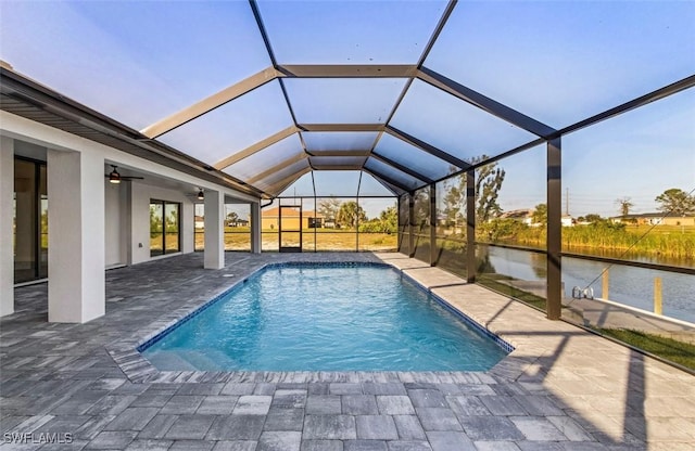 view of pool featuring ceiling fan, a water view, a patio area, and glass enclosure