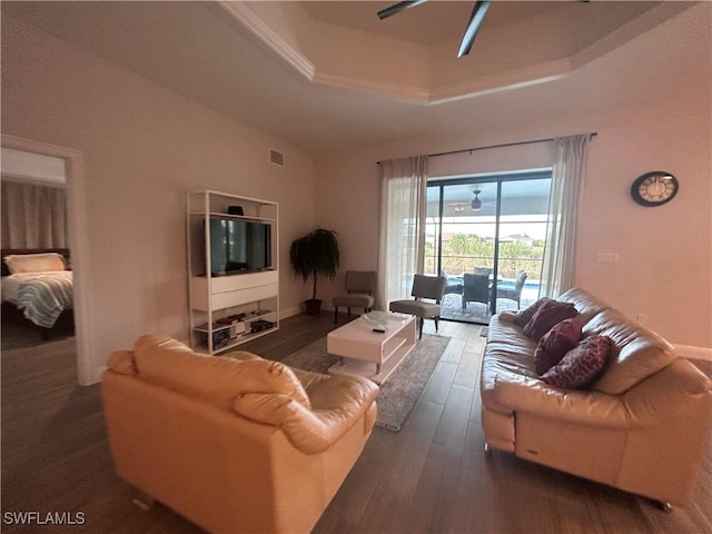 living room featuring a tray ceiling, ceiling fan, and dark wood-type flooring