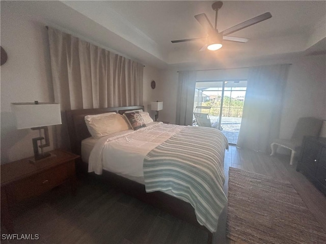 bedroom featuring access to outside, ceiling fan, a tray ceiling, and dark hardwood / wood-style floors