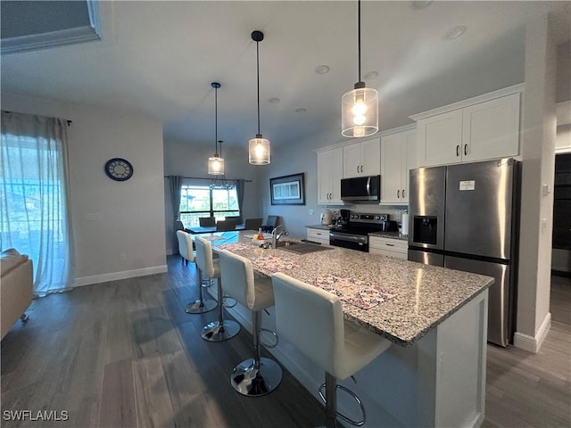 kitchen featuring a breakfast bar, white cabinets, sink, an island with sink, and stainless steel appliances