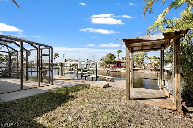 view of yard with glass enclosure, a water view, and a dock