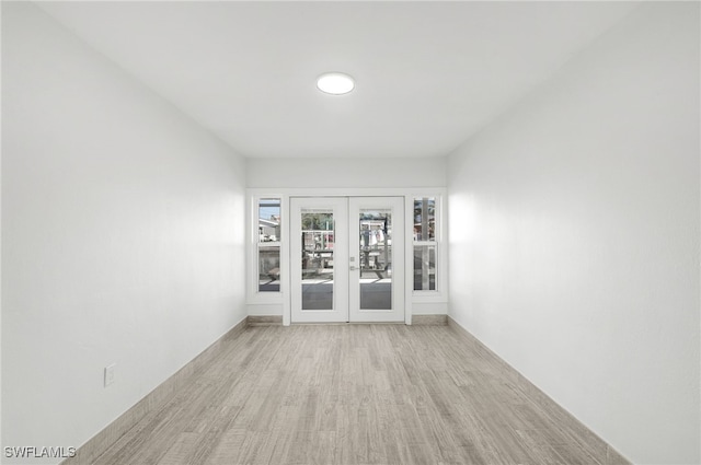 empty room with light hardwood / wood-style floors and french doors