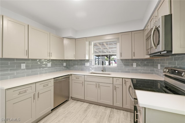 kitchen with backsplash, light hardwood / wood-style floors, sink, and stainless steel appliances