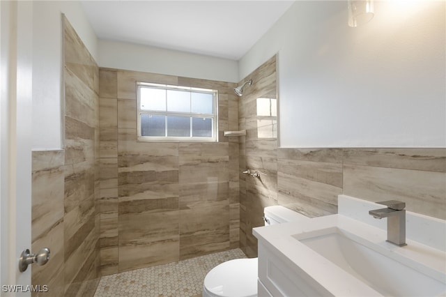 bathroom with a tile shower, sink, tile walls, and toilet