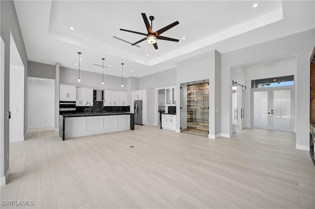 kitchen featuring white cabinetry, french doors, hanging light fixtures, a tray ceiling, and appliances with stainless steel finishes