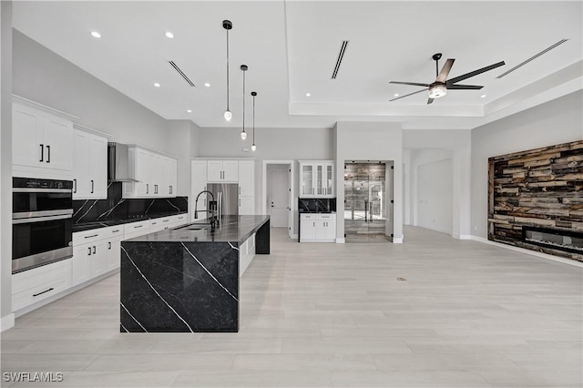 kitchen with sink, hanging light fixtures, a center island with sink, white cabinets, and appliances with stainless steel finishes