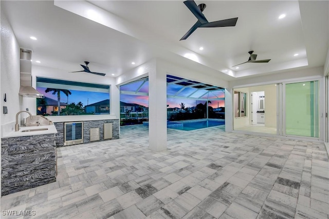 patio terrace at dusk with wine cooler, area for grilling, a lanai, and a wet bar