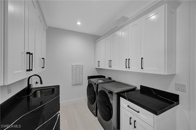 laundry room featuring cabinets, independent washer and dryer, sink, and light wood-type flooring