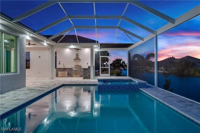 pool at dusk featuring a patio area, ceiling fan, a lanai, area for grilling, and an in ground hot tub