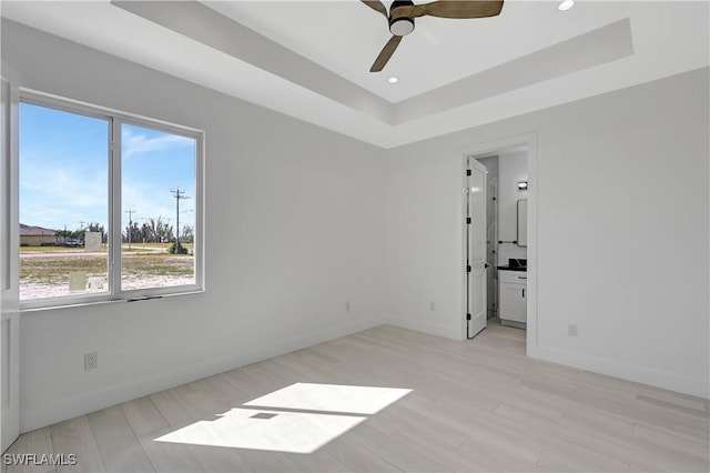 spare room with ceiling fan and a raised ceiling