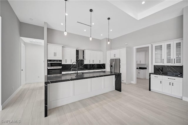 kitchen featuring pendant lighting, stainless steel fridge, white cabinets, and a high ceiling