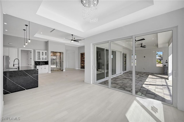 living room with ceiling fan with notable chandelier and a raised ceiling