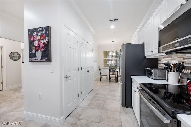 kitchen with tasteful backsplash, appliances with stainless steel finishes, decorative light fixtures, white cabinets, and ornamental molding