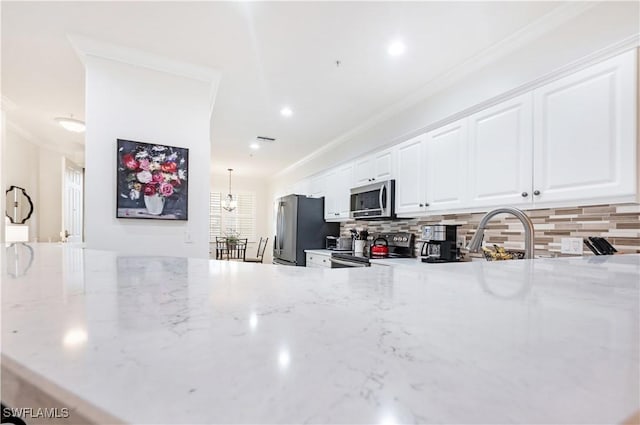 kitchen with light stone countertops, tasteful backsplash, crown molding, white cabinets, and appliances with stainless steel finishes